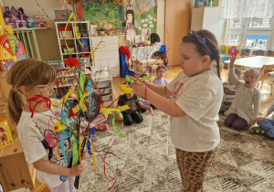 Dziewczynka wiąże na gałązce wstażkę