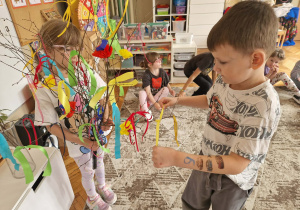 Chłopiec wiąże zółtą wstążkę do gałazki