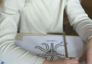 Dziewcyznka przy stoliku koloruje Marzannę