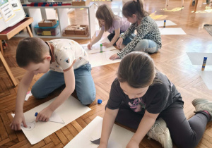 Dzieci na podłodze z elementów układają bociany