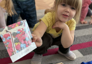 Dziewczynka pokazuje obrazek owoców