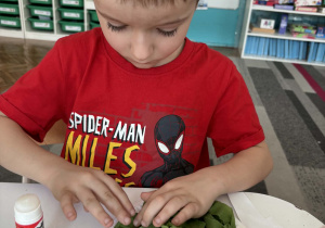 Chlopiec przykleja biibułę na talerzyk