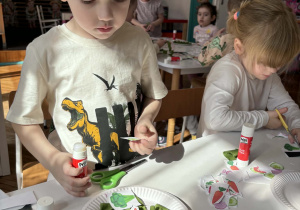 Chłopiec układa na talerzu wycięte warzywa