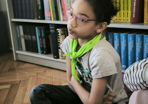 Chłopiec siedzi na pufie w biblotece