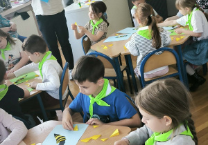 Dzieci sklejaja pszczoły siedząc przy stolikach