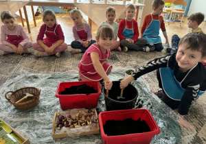 Dzieci nabierają i wsypują ziemię do doniczek