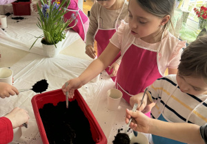 Dzieci nabiejają z pojemnika ziemię