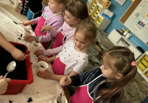 Dziewczynki wsypują ziemię do doniczek