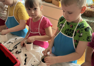 Chłopiec wkłada cebulkę rośliny do doniczki