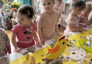 Dwie dziewczynki przy stole pracują nad dekoracją swich pisanek