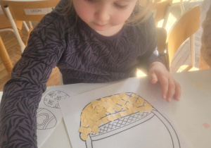 Dziewczynka wykleja koszyczek kwadratami