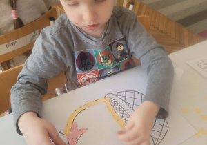 Chłopiec wykleja na różowo kokardę