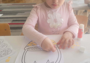 Dziewczynka przykleja kwadraciki na koszyczek