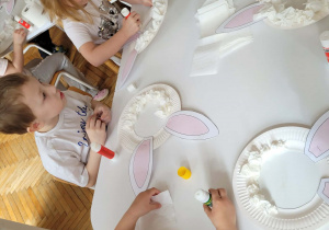 Dzieci przyklejają papier toaletowy na talerzyk papierowy