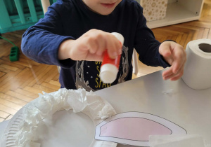 Chłopiec przykleja papier toaletowy na okrąg talerzyka