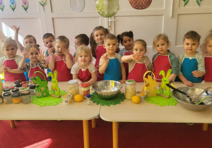 dzieci stoją przed stołem w fartusszkach