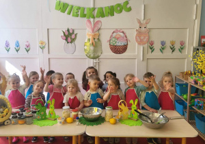 dzieci stoją przed stołem w fartusszkach