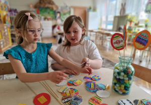 Dziewczynki wycinają i naklejają jajka