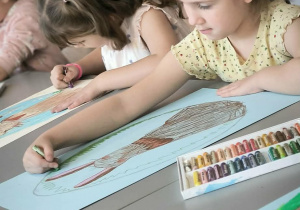 Dziewczynka koloruje pisankę z królikiem