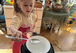 Dziewczynka odmierza do szklanki cukier