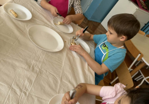 Dzieci obieraczkami obierają korzeń chrzanu