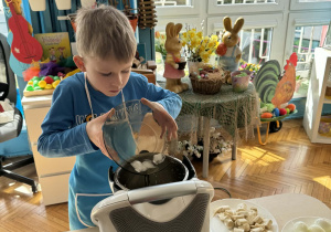 Chłopiec do miksera dodaje kostki lodu
