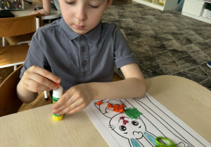 Chłopiec kulkami wykleja marchewkę królika