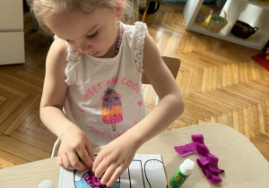 Dziewczynka koloruje spodenki królika na niebiesko