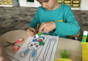 Chłopiec pomarańczowymi kulkami wykleja marchewkę królika