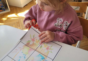 Dziewczynka wycina nożyczkami przy stole