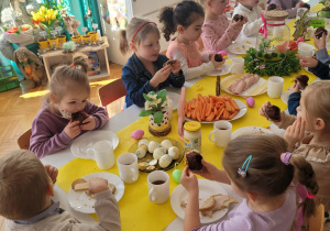 Dzieci przy stole jedzą śłodkie ciastk i babeczki