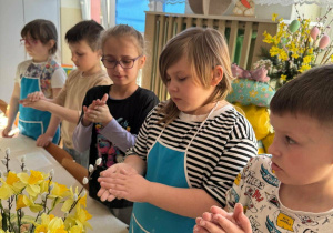 Dzieci obtaczają ręce w mące