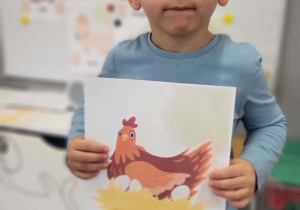 chłopiec prezentuje plansze z kurą