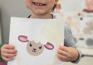 chłopiec prezentuje plansze z owcą