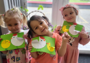 troje dzieci pokazuje swoje prace plastyczne