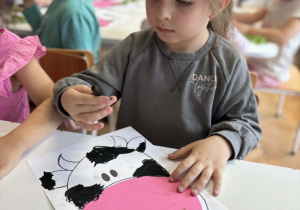 Dziewczynka kredką pastelową maluje łaty krowy