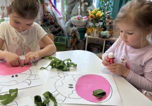 Dzieci przy stoliku przyklejają zieloną bibułę