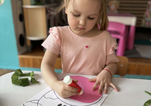 Dziewczynka klei klejem różowy karton