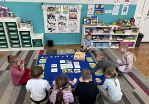 Dzieci siedza przed ilustracjami wiejskiej zagrody