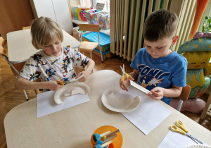 Chłopcy przecinają talerzyk papierowy