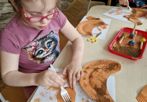 Dziewczynka skrobie farbę widelcem