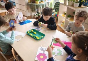 Dzieci przy stole wycinają kwiaty