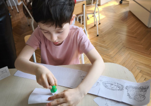 Chłopiec przykleja obrazek historyjki obrazkowej