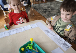 Dzieci siedząp rzy stole i układają historyjkę