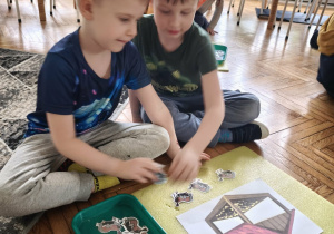 Chłopcy przliczają i ukladają ptaki pod karmnikiem