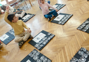 Dzieci siedzą na dywanie z kartkami krowy i liczbami