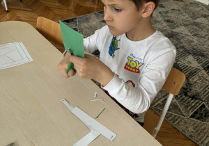 Chłopiec wycina figury nożyczkami