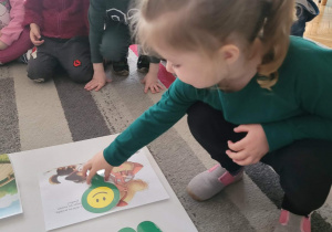 Dziewczynka uklada znaczek uśmiechniętej buzi