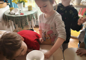 Dziewczynka kładzie fasole na gazie