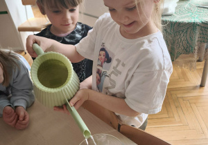 Dziewczynka wlewa wodę do naczynia